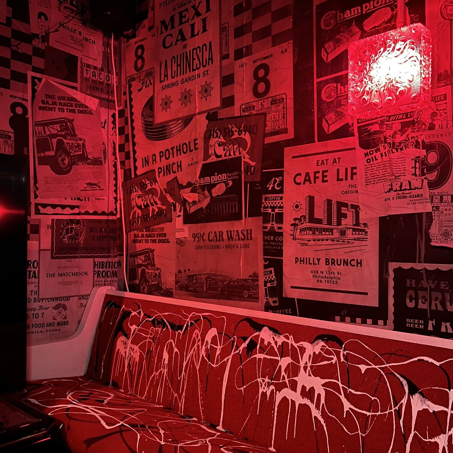 Poster strewn wall and paint splattered bench bathed in red light